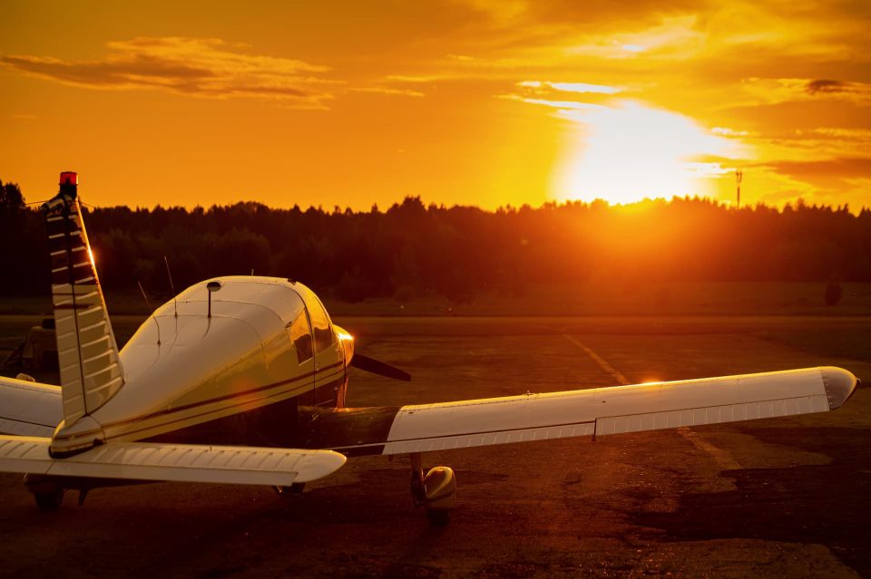 A light aircraft parked facing the sunset, rear view